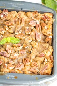 A baked dessert in a square pan topped with pecan halves and a sprig of fresh mint, featuring a golden-brown, crumbly surface.