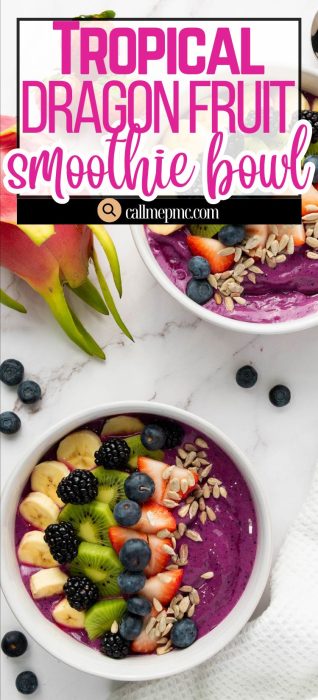 Two dragon fruit smoothie bowls topped with sliced banana, kiwi, strawberry, blueberries, blackberries, sunflower seeds, and granola sit on a marble surface alongside a whole dragon fruit.