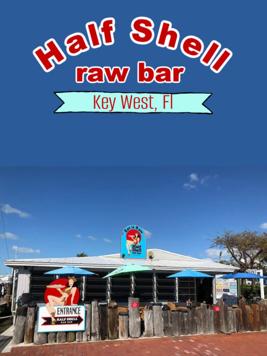 The front of Half Shell Raw Bar featuring a blue sign with a retro pin-up logo, a wooden exterior, and a large banner above—an iconic spot for anyone.