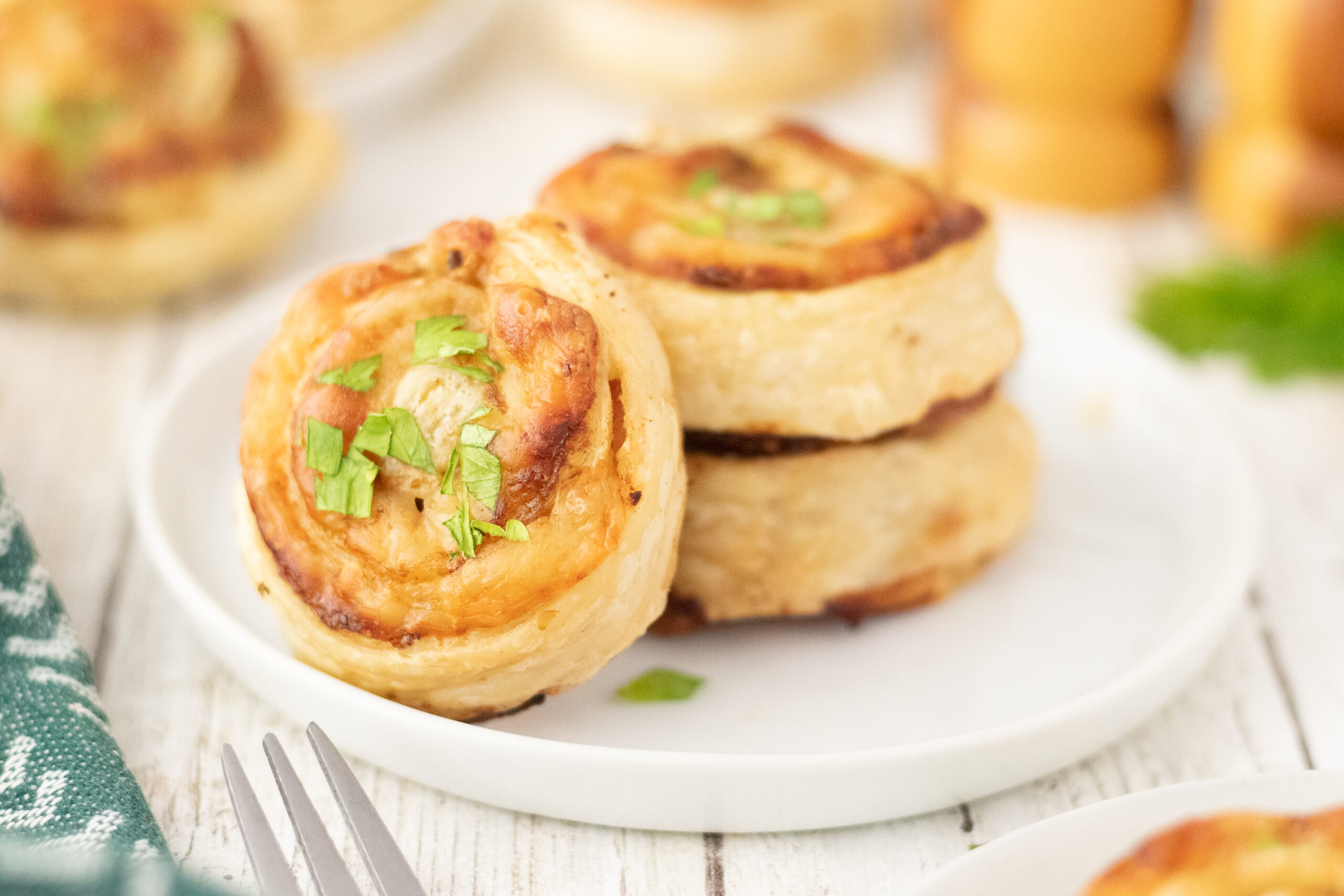 Three savory appetizers topped with fresh herbs on a white plate.