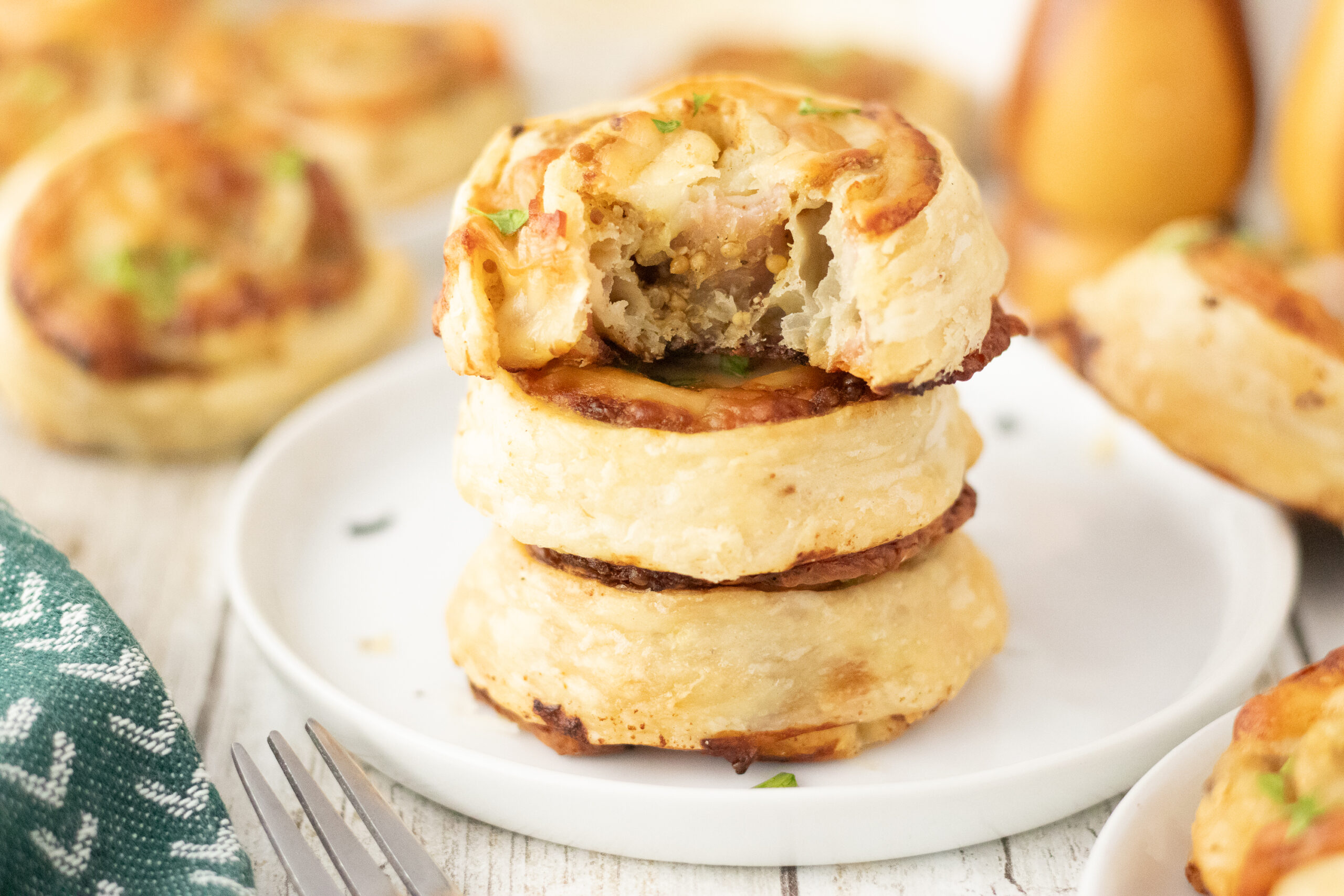 A stack of three savory biscuits on a small white plate, with a bite taken out of the top one.