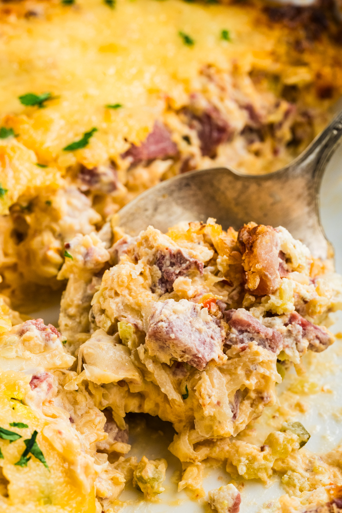 A spoonful of casserole appetizer containing being lifted from a baking dish.