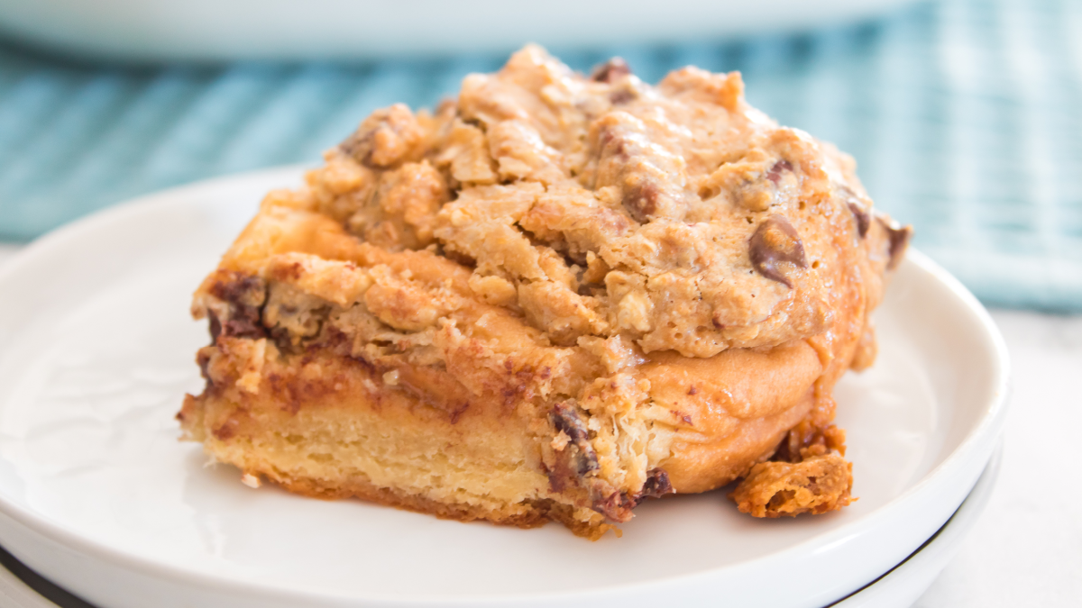A square serving of Texas Trash sticky buns topped with a thick, textured layer of nuts and brown sugar on a white plate.
