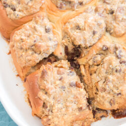 A baking dish filled with Texas Trash sticky buns, which are pull-apart sweet rolls topped with a crumbled pecan and chocolate chip streusel.