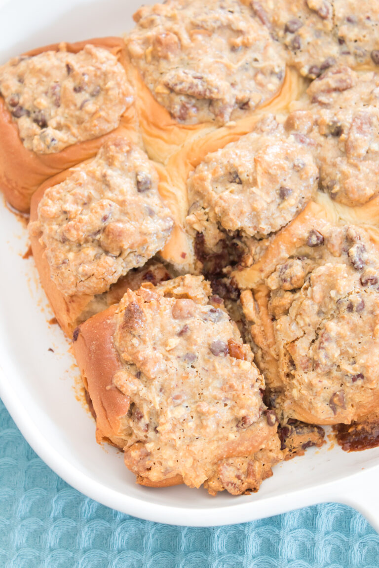 A baking dish filled with Texas Trash sticky buns, which are pull-apart sweet rolls topped with a crumbled pecan and chocolate chip streusel.